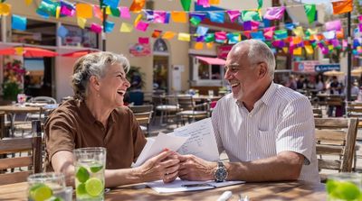 Retired American couple celebrating dental savings at Los Algodones café with mariachi band