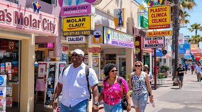 Diverse American tourists walking past colorful dental clinic signs on Los Algodones main street