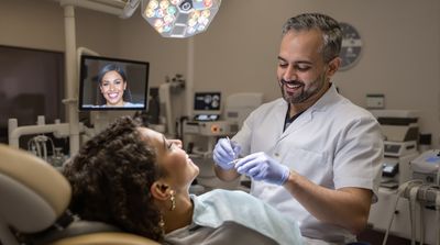 Dentist performing precision final fitting adjustment while patient admires new all-on-4 dentures.
