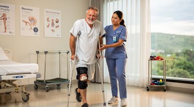 Patient walking with assistance during knee recovery in Mexico.