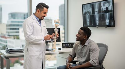 A surgeon demonstrates the LON hybrid method using a 3D model during a consultation with a patient in an orthopedic office.